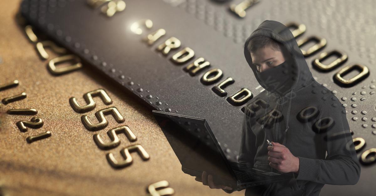 Computer hacker with laptop against background with credit cards