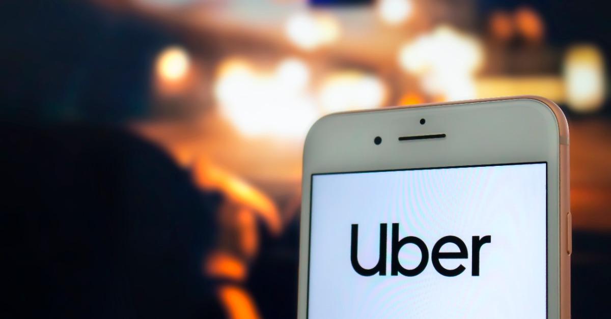 An iPhone Plus hold by a passenger with the Uber logo on the screen