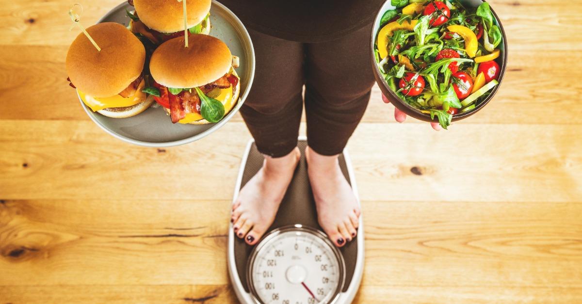 Healthy young woman looking at healthy and unhealthy plates of food