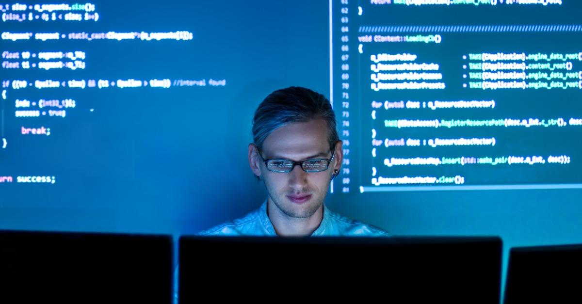 Software developer work with program code C Java Javascript on wide displays at night