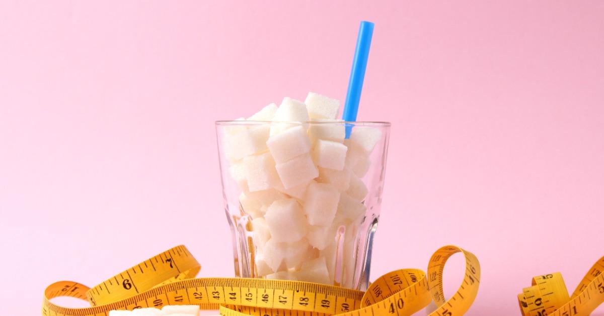 sugar in a glass and measuring tape on a colored background
