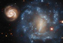 這對宇宙銀河看起來像是一個小型、活躍的螺旋星系在圍繞一個更大、更陰暗的夥伴旋舞，但這種排列其實只是視角造成的錯覺。（圖／ESA）