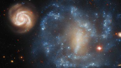 這對宇宙銀河看起來像是一個小型、活躍的螺旋星系在圍繞一個更大、更陰暗的夥伴旋舞，但這種排列其實只是視角造成的錯覺。（圖／ESA）