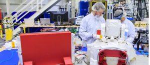 在甘迺迪太空中心，林肯實驗室（Lincoln Laboratory）人員 Justin Dunbeck（左）與 Steven Constantine 正在拆封並檢查 NASA 阿提米絲二號（Artemis II）登月任務所使用的光學通訊系統酬載。（圖／Glenn Benson/NASAGlenn Benson/NASA）