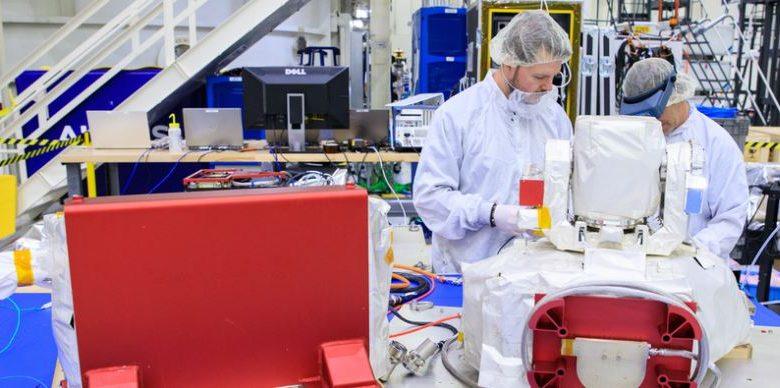 在甘迺迪太空中心，林肯實驗室（Lincoln Laboratory）人員 Justin Dunbeck（左）與 Steven Constantine 正在拆封並檢查 NASA 阿提米絲二號（Artemis II）登月任務所使用的光學通訊系統酬載。（圖／Glenn Benson/NASAGlenn Benson/NASA）