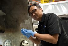 NASA蘭利研究中心SPEARS計畫測試與研究負責人Yi Lin，手持一顆剛完成熱真空測試的小型鈕扣型電池。（圖／NASA／Ryan Hi）
