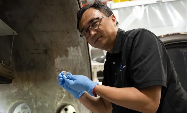NASA蘭利研究中心SPEARS計畫測試與研究負責人Yi Lin，手持一顆剛完成熱真空測試的小型鈕扣型電池。（圖／NASA／Ryan Hi）
